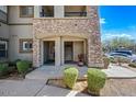 Ground level entrance to condo featuring stone accents, stairs to upper level, and landscaped bushes at 19700 N 76Th St # 2044, Scottsdale, AZ 85255