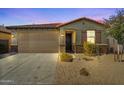 Single-story home at dusk featuring a brown garage door and desert landscaping at 20056 N 107Th Ln, Peoria, AZ 85373