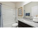 Well-lit bathroom with granite countertops, shower and tub, and a white cabinet at 28228 N Nealite Dr, San Tan Valley, AZ 85143