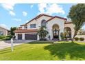Two-story home showcasing a tile roof, three-car garage, arched entryway, and verdant lawn with a real estate sign at 9159 N 108Th Pl, Scottsdale, AZ 85259