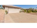 Spacious driveway leads to the two-car garage with desert landscaping accents at 10410 E San Tan Blvd, Sun Lakes, AZ 85248