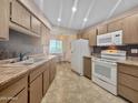 Functional kitchen with a dining table near the white appliances and wood-look cabinets at 10906 W Thunderbird Blvd, Sun City, AZ 85351