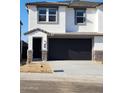 Modern two-story home featuring a dark garage door, white stucco, stone accents, and neat landscaping at 1111 E Mcneil St, Phoenix, AZ 85044