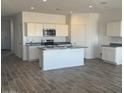 Modern kitchen features white cabinets, stainless steel appliances, and a large center island with granite countertops at 1404 W Kennedy Ave, Coolidge, AZ 85128