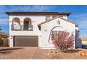 Charming two-story home with balconies, desert landscaping, and a brown two-car garage at 18268 W Carol Ave, Waddell, AZ 85355