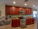 Well-lit kitchen featuring stainless steel appliances, warm-toned cabinetry, and granite countertops at 23882 W Yavapi St, Buckeye, AZ 85326