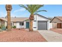 Single story home with xeriscape front yard, palm trees and a teal front door at 3026 W Ross Ave, Phoenix, AZ 85027