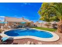 A stunning backyard features a swimming pool, spa, green lawn, and patio with comfortable seating at 5462 W Geronimo St, Chandler, AZ 85226