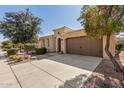 Charming single-story home with desert landscaping, a brown two car garage, and an arched entryway at 815 E Laddoos Ave, San Tan Valley, AZ 85140