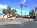 Entry to the community, highlighting the beautifully landscaped roundabout with mature trees, palms, and community sign at 10115 E Mountain View Rd # 1119, Scottsdale, AZ 85258