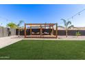 Beautiful backyard with wooden pergola, lush green grass, gravel landscaping, mature palm trees creating a relaxing outdoor oasis at 1781 S 223Rd Dr, Buckeye, AZ 85326