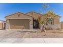 Inviting home exterior with a two-car garage, desert landscaping, and a well-maintained lawn at 1781 S 223Rd Dr, Buckeye, AZ 85326