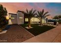 Contemporary home with a green lawn, palm trees, and gravel driveway during a colorful sunset at 2642 N Fiesta St, Scottsdale, AZ 85257