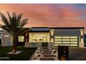 Modern home showcasing a well-lit pathway, glass garage door, and freshly landscaped front yard at dusk at 2642 N Fiesta St, Scottsdale, AZ 85257