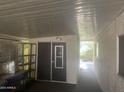 Storage area with door, shelving, cement floor and ceiling, and open view to outdoor greenery at 2744 N Trevino Pl, Mesa, AZ 85215