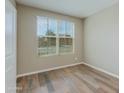 Clean, minimalist bedroom with wood-look floors, natural light from a large window, and neutral wall color at 287 N Jesse St, Chandler, AZ 85225