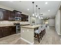 Open kitchen with dark wood cabinetry, granite countertops, a spacious island with seating, and stainless steel appliances at 287 N Jesse St, Chandler, AZ 85225