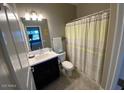 A bathroom with a shower, toilet, and a sink with a dark-colored vanity at 29573 W Mitchell Ave, Buckeye, AZ 85396