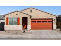 Charming single-story home showcasing a desert landscape, and an eye-catching orange garage door with matching shutters at 37056 W Prado St, Maricopa, AZ 85138