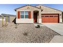 This house boasts a well-maintained desert front yard with a vibrant orange garage door and matching window shutters at 37056 W Prado St, Maricopa, AZ 85138