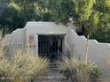 A gated entrance with an ornate metal gate in a walled entrance and mature trees at 6242 E Maverick Rd, Paradise Valley, AZ 85253