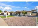 Single-story home featuring a gravel yard, attached garage, and chairs on a covered patio at 8215 E Cypress St, Scottsdale, AZ 85257