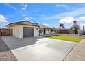 A single-story house featuring an attached garage, a large driveway, and artificial turf in the front yard at 8215 E Cypress St, Scottsdale, AZ 85257