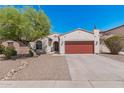 Inviting home featuring desert landscaping, a red garage door, and a lush, mature tree at 10212 W Wier Ave, Tolleson, AZ 85353