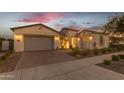 Charming single-story home with a three-car garage, brick paved driveway, and manicured landscaping at dusk at 10455 E Thornton Ave, Mesa, AZ 85212