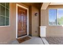 Close-up of an elegant wood front door with a 'Welcome To Our Home' mat and stylish hardware at 119 W Leatherwood Ave, San Tan Valley, AZ 85140