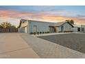 Expansive view of a light gray home with three-car garage, showcasing the driveway and manicured landscaping at 11942 N 95Th St, Scottsdale, AZ 85260