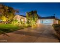 Inviting home exterior featuring manicured landscaping, warm exterior lighting, and a spacious driveway at twilight at 2125 W Berridge Ln, Phoenix, AZ 85015