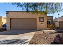 Beige single-story home exterior with a two-car garage, desert landscaping, and a secure entry gate at 2129 N Apollo Ct, Chandler, AZ 85224