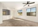 Bright and airy carpeted living room with two large windows, and a ceiling fan at 37808 N Pagoda Ln, Phoenix, AZ 85086