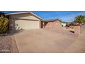 View of house exterior showcasing a large driveway, desert landscaping, and an attached garage at 5618 E Des Moines St, Mesa, AZ 85205