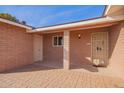 Covered front porch featuring brick flooring, a security door, and convenient access to the home at 5618 E Des Moines St, Mesa, AZ 85205