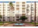 Exterior view of a multi-story building with palm trees surrounding a water fountain and well-maintained green spaces at 7830 E Camelback Rd # 108, Scottsdale, AZ 85251