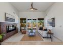 Bright living room featuring a fireplace, white sofa, ceiling fan, and French doors leading to the backyard at 9214 N 83Rd St, Scottsdale, AZ 85258