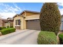 A tan single-Gathering home with a two-car garage, well-maintained landscaping, and a concrete driveway at 9610 E Trent Ave, Mesa, AZ 85212