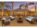 Inviting backyard patio with comfortable seating, lush palm trees, and a charming water feature perfect for outdoor relaxation at 22837 E Silver Creek Ln, Queen Creek, AZ 85142
