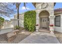 Inviting front entrance with decorative planters and a stone bench, framed by a lush green shrub and stucco walls at 4010 E Grandview St, Mesa, AZ 85205