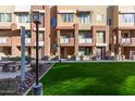 Townhome exterior view displaying a green communal lawn, shade structure, and colorful facades at 6605 N 93Rd Ave # 1022, Glendale, AZ 85305