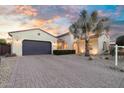 Home featuring a wide driveway, desert landscaping, and a charming facade under a colorful sky at 15837 W Bonitos Dr, Goodyear, AZ 85395