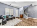 Inviting living room with wood floors and staircase, gray sofa, and natural light at 16585 W Harrison St, Goodyear, AZ 85338