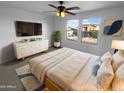 This bedroom has a ceiling fan, large windows, dresser, and neutral-toned rug at 17699 W Tonto St, Goodyear, AZ 85338