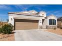 Attractive single-story home featuring a two-car garage, desert landscaping, and stone veneer accents at 30940 W Indianola Ave, Buckeye, AZ 85396