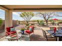 Inviting covered patio with comfortable seating and a view of the landscaped backyard at 41012 N Noble Hawk Way, Anthem, AZ 85086