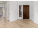 Bright entryway featuring light wood floors, white walls, and a solid wood front door at 41401 N Maidstone Ct, Anthem, AZ 85086