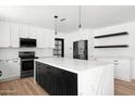 Modern kitchen with a large island, stainless appliances, white cabinets, and wood-look flooring at 8525 E Clarendon Ave, Scottsdale, AZ 85251