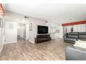 Open floor plan with wood floors, a large TV, and a view into the kitchen at 902 S Saranac Ave, Mesa, AZ 85208